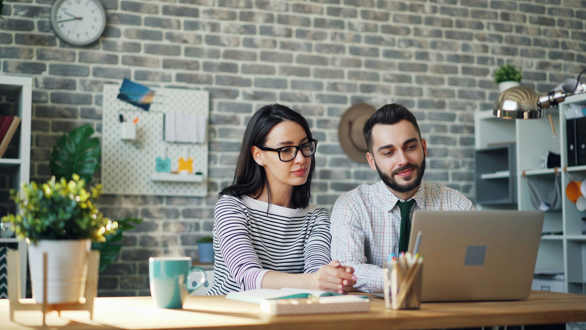 a-man-and-woman-sitting-at-a-table-looking-at-a-laptop